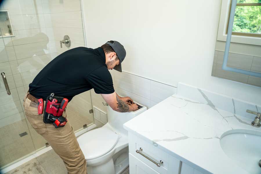 Professional Mrs. Michael plumber inspecting and fixing a leaking toilet tank to stop ghost flushing.